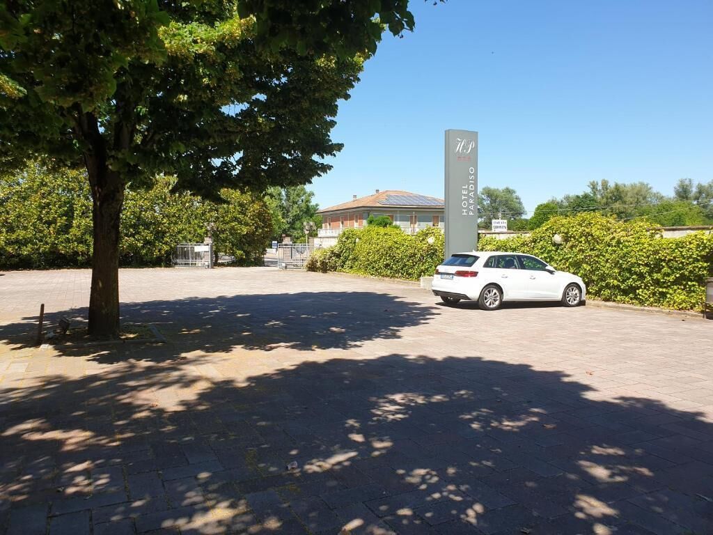 A white car parked in front of a hotel named "Hotel Paradiso."