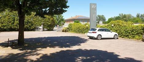 A white car parked in front of a hotel named "Hotel Paradiso."