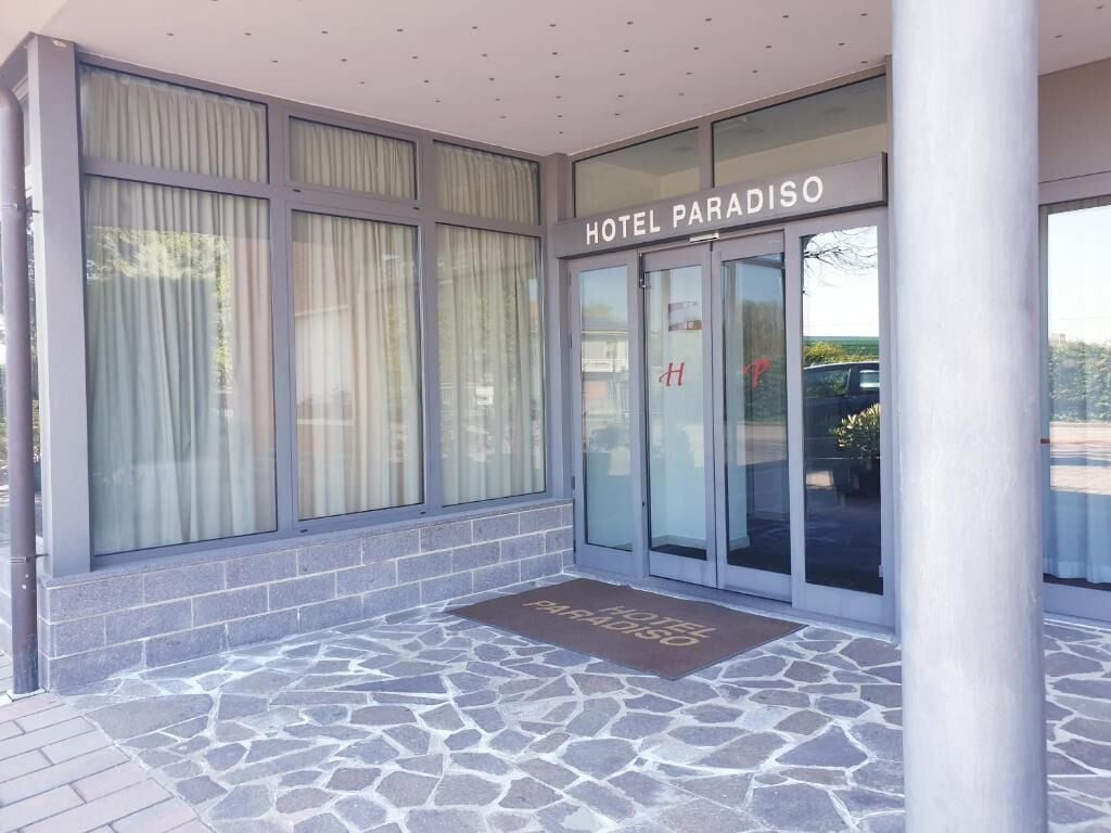 The entrance of Hotel Paradiso with a stone-tiled entrance and a glass door with a visible 'H' logo.