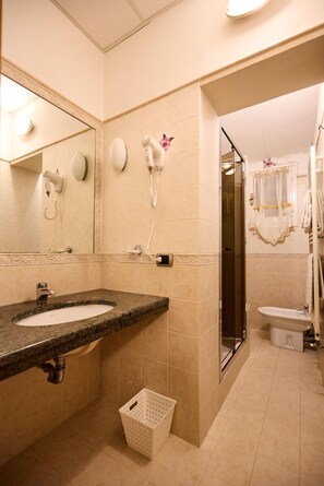 A bathroom with a sink, mirror, hairdryer, and shower. - HOTEL PARADISO (Malalbergo)