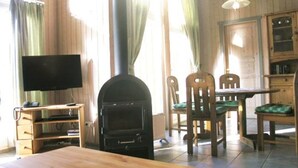 Una habitación acogedora con una chimenea de leña, un televisor y un comedor con sillas y una mesa.