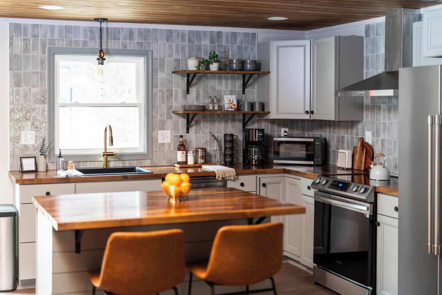 A modern kitchen with a central island, stainless steel appliances, and a window providing natural light.