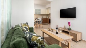 A modern living room with a green sofa, a wooden coffee table, and a flat-screen TV mounted on the wall. - Levanta Cozy Apartment 3 in Kalavarda Rhodes (Rhodes)