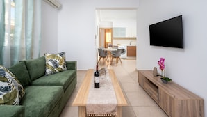 A modern living room with a green sofa, a wooden coffee table, and a flat-screen TV mounted on the wall. - Levanta Cozy Apartment 3 in Kalavarda Rhodes (Rhodes)