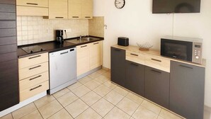 A compact kitchen with a dishwasher, a microwave, a coffee maker, and a clock on the wall. - T2 beach walk - family relaxation (Linguizzetta)