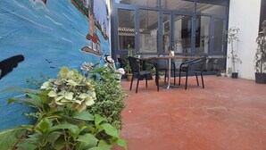 An outdoor patio area with a mural, a table with chairs, and potted plants. - Grand Bedir (Istanbul)