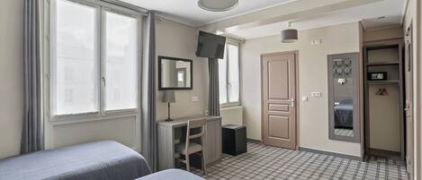 A hotel room with two beds, a desk, a chair, a television, and a wardrobe.