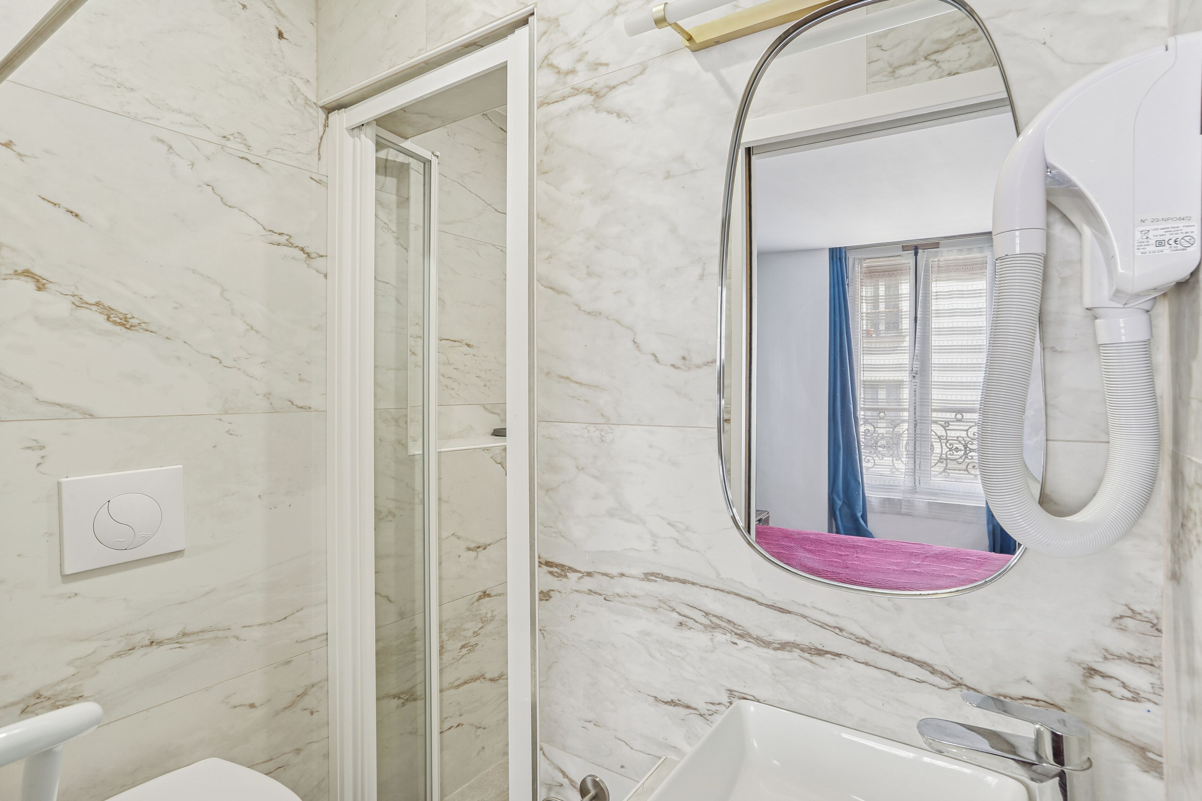 A bathroom with a marble floor, a white sink, a mirror, and a hairdryer.