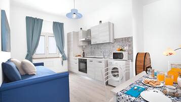 A modern, compact living space with a kitchenette, a dining area, and a bedroom.