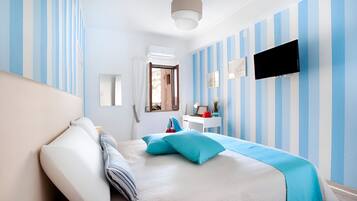 A hotel room with a bed, a desk, a TV, and a window with curtains.