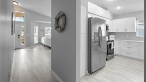 Une cuisine moderne avec des armoires blanches, des appareils en acier inoxydable et un plancher en bois clair.