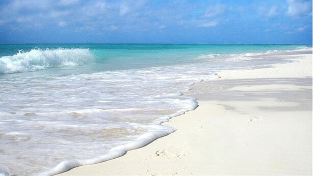 Une plage à l’eau turquoise et au sable blanc.