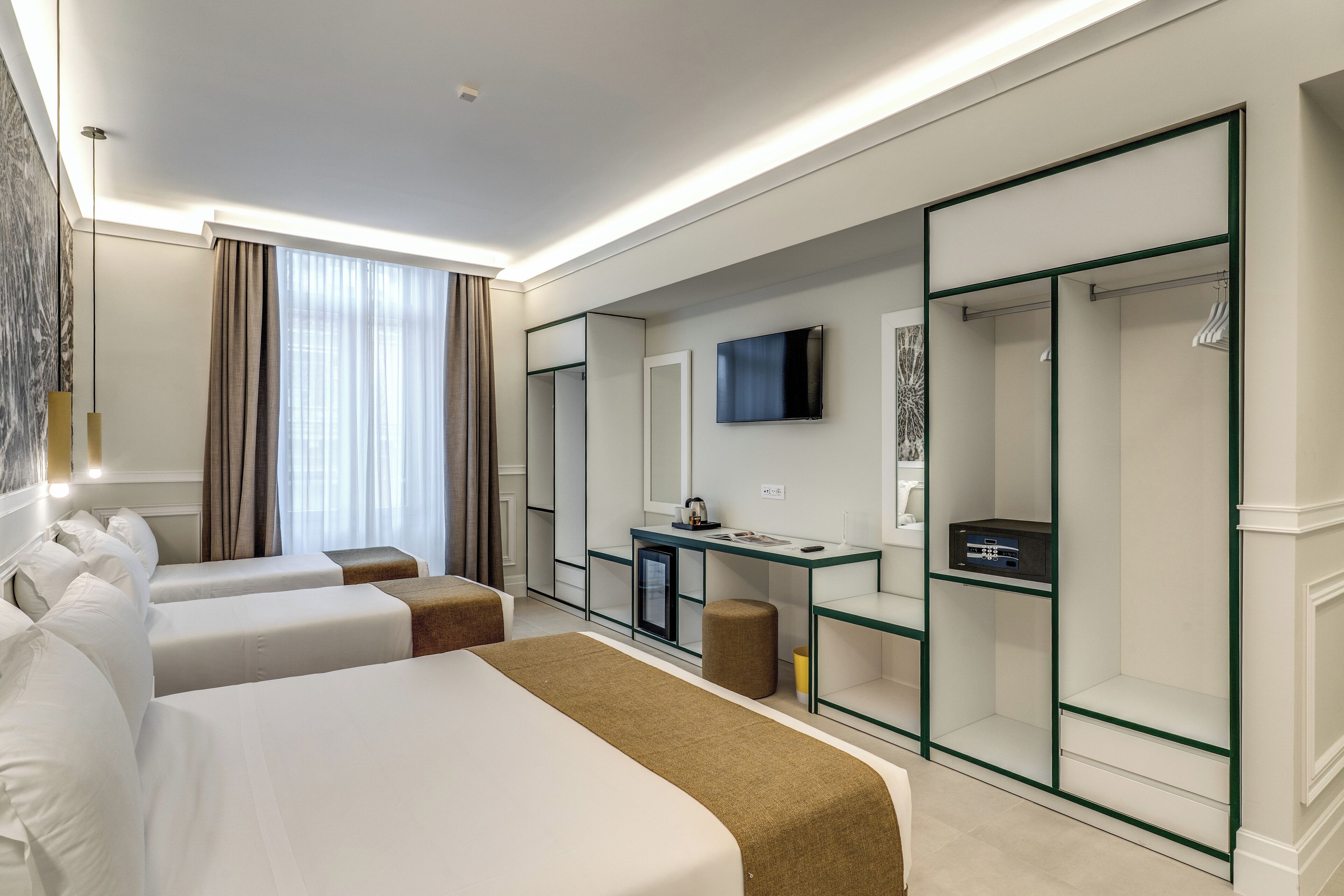 A hotel room with two beds, a desk, a TV, and a wardrobe.