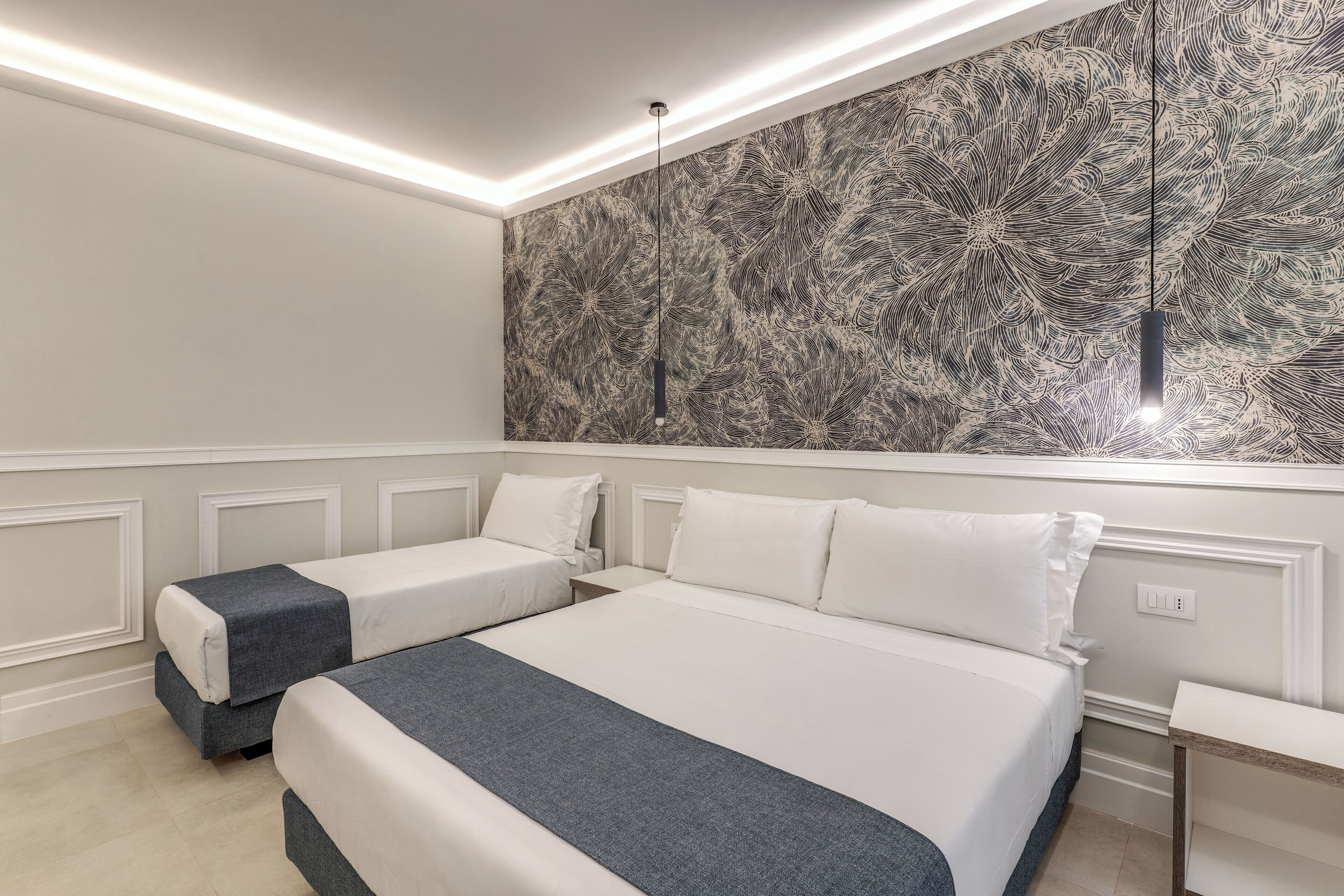 A hotel room with two single beds, a large wall mural, and a modern pendant light.