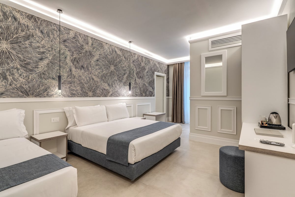 A modern hotel room with a large bed, bedside tables, a desk, and a decorative wall.