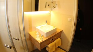 Un baño con cabina de ducha de vidrio, lavamanos y espejo.