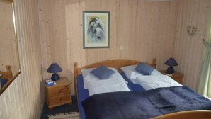 Ein Schlafzimmer mit Holzwänden, einem Bett, zwei Nachttischen und einem Bild an der Wand.