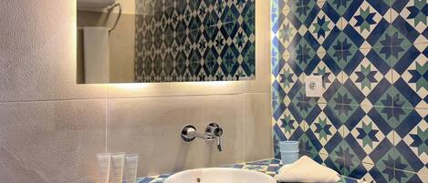 A bathroom with a white sink, a mirror, and a patterned tile backsplash.