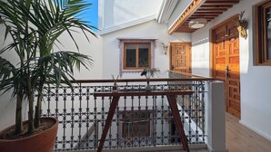 A balcony with a potted plant, a wooden table, and a view of a wooden door and window. - DAR TAHAR (Rabat)