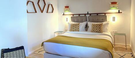 Un dormitorio moderno con cama, mesitas de noche y apliques decorativos.