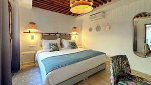 A bedroom with a bed, bedside lamps, a mirror, and a chair. - DAR TAHAR (Rabat)