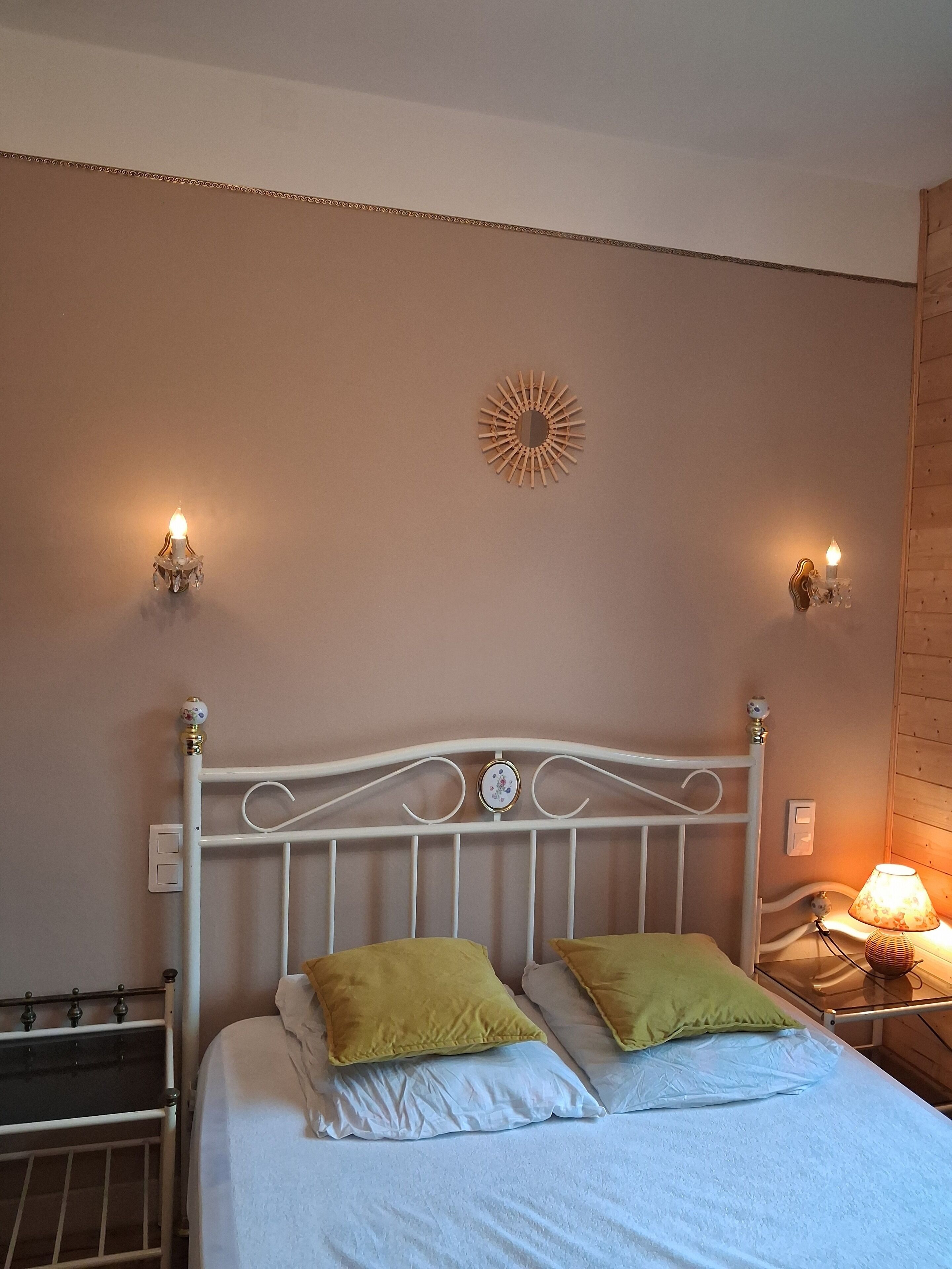A bed with white bedding, two pillows, a decorative wall piece, and two wall-mounted lamps.