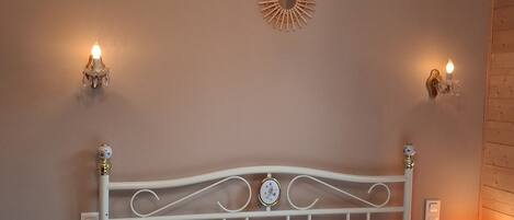A bed with white bedding, two pillows, a decorative wall piece, and two wall-mounted lamps.