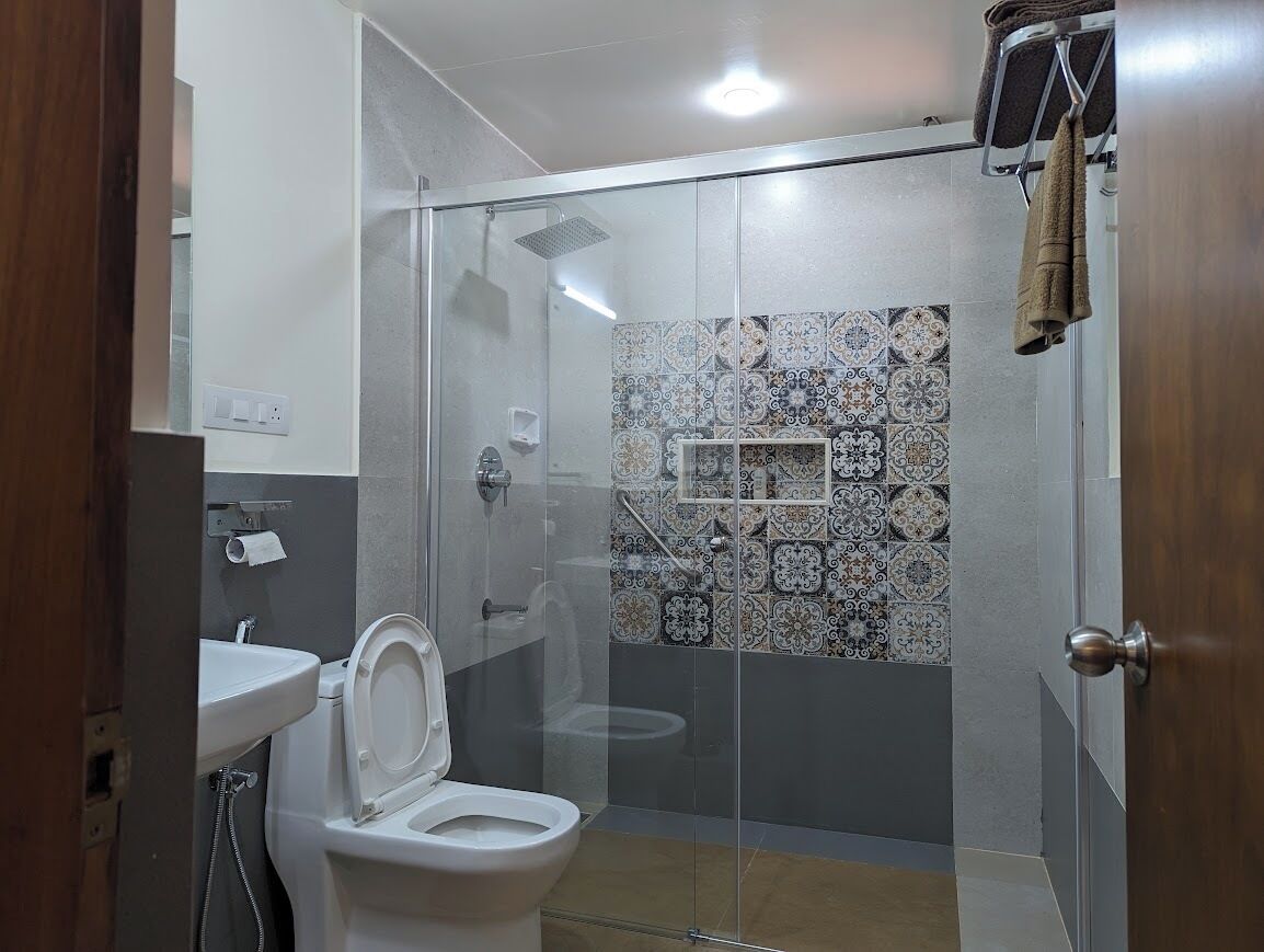 Ein modernes Badezimmer mit einer Glaskabine zur Dusche, einer Toilette mit erhöhtem Sitz und einem Waschbecken.