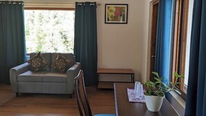 A dining area with a wooden table, chairs, a bench, and a potted plant. - Villa #248 (Somvarpet)