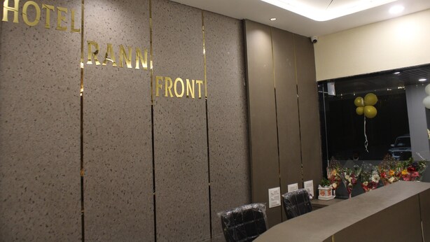 A hotel reception desk with a sign reading "HOTEL FRONT" and a window with balloons.