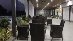 A covered outdoor seating area with wicker furniture and potted plants.