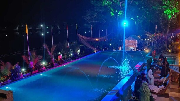 Ein Poolbereich mit Wasserspiel, umgeben von Pflanzen und Lichterketten.