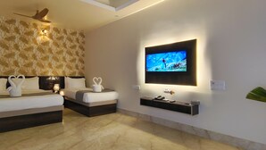 Ein modernes Hotelzimmer mit großem Flachbildfernseher an der Wand, Deckenventilator und einer dekorativen Wandverkleidung.