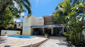 A two-story building with a covered patio area, a swimming pool, and surrounding tropical vegetation. - Salty Chateau: Private Exquisite Mauritian Getaway (Cap Malheureux)