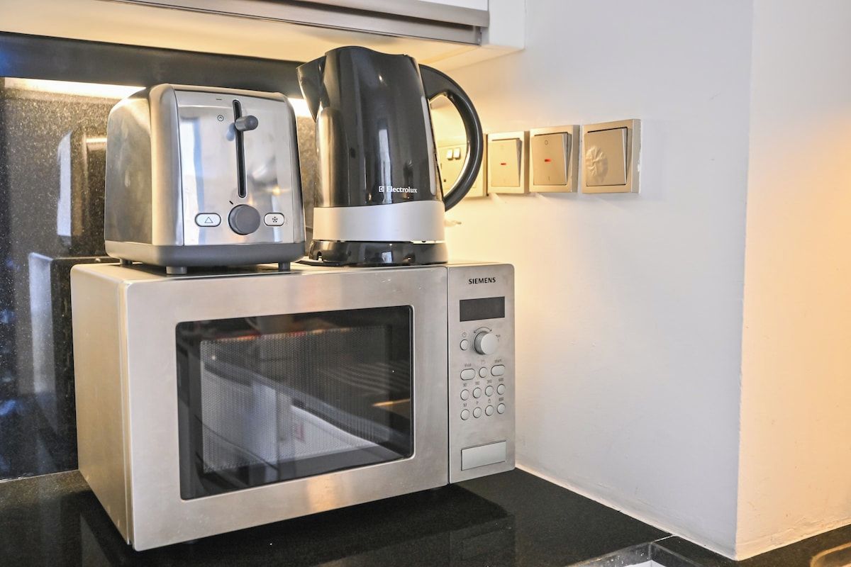 A kitchen with a microwave oven, a toaster, and a coffee maker.