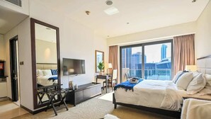 Une chambre d’hôtel avec un grand lit, un bureau, une chaise, une télévision et une vue sur le paysage urbain.