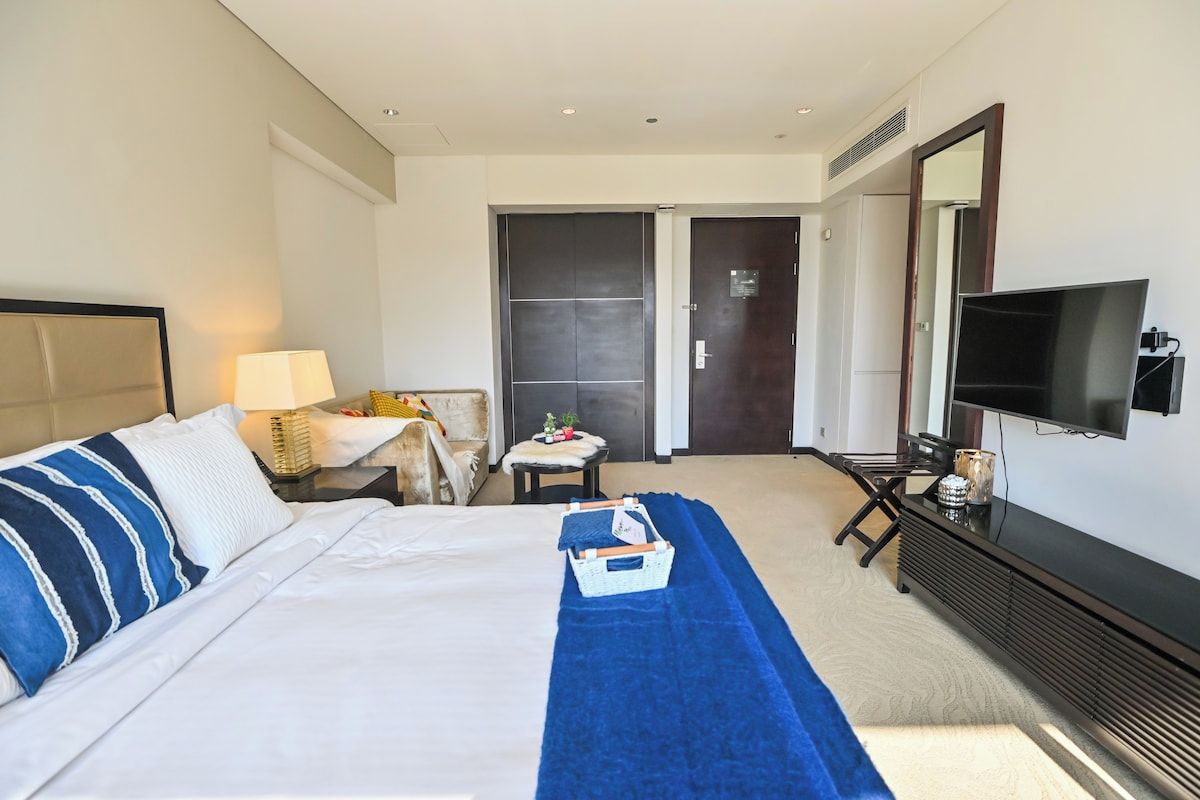 A hotel room with a bed, a television, a desk, and a chair.
