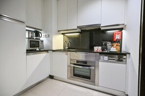 Cozinha moderna com eletrodomésticos de aço inoxidável, incluindo micro-ondas, forno e lava-louças.