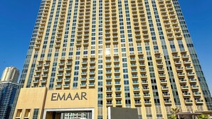 Een hoog hotel met een zwembad ervoor.