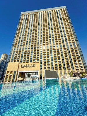Hotel alto com piscina na frente.