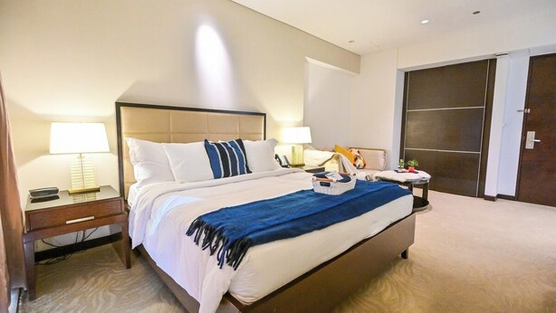 Een hotelkamer met een groot bed, nachtkastjes, een lamp, een garderobe en een tapijtvloer.