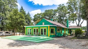 Un edificio verde y amarillo con un porche cubierto y un camino de entrada de grava.