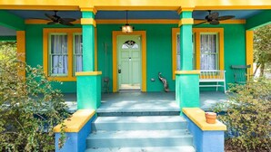 Una casa de colores vivos con un porche, escalones que conducen a la entrada y una puerta con un ventilador encima.