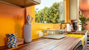 A modern kitchen with a wooden countertop, a large window with a view of trees, and a coffee machine.