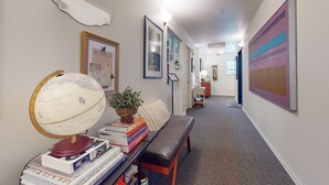 A hallway with a globe, books, a bench, and framed artwork. - The Washington Hotel (Port Townsend)