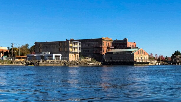 A waterfront building with multiple stories, a dock, and a clear blue sky. - The Washington Hotel (Port Townsend)