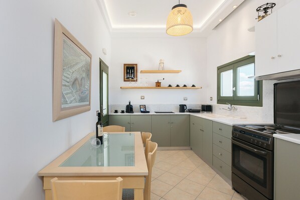 A modern kitchen with a dining table, a stove, and a hanging light fixture.