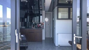 Una cocina moderna con estufa integrada, un pequeño comedor y vistas al mar a través de grandes ventanales.