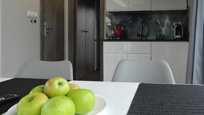 Una mesa de comedor con un plato de manzanas verdes, un control remoto y un mantel individual gris.