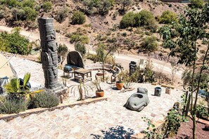 A patio with stone flooring, outdoor furniture, and potted plants.